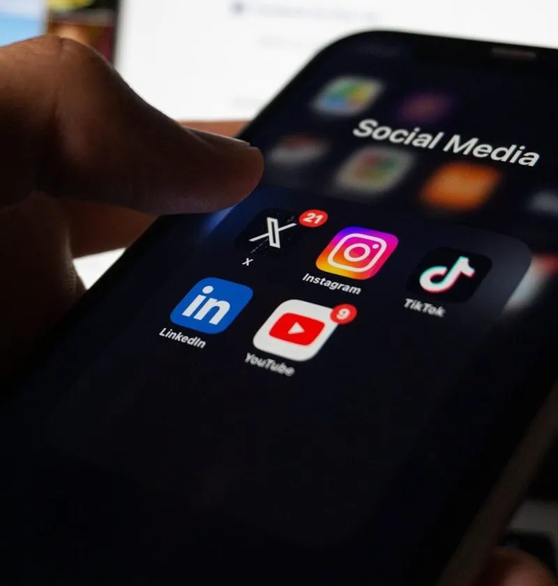 A person holding a smart phone with social media on the screen